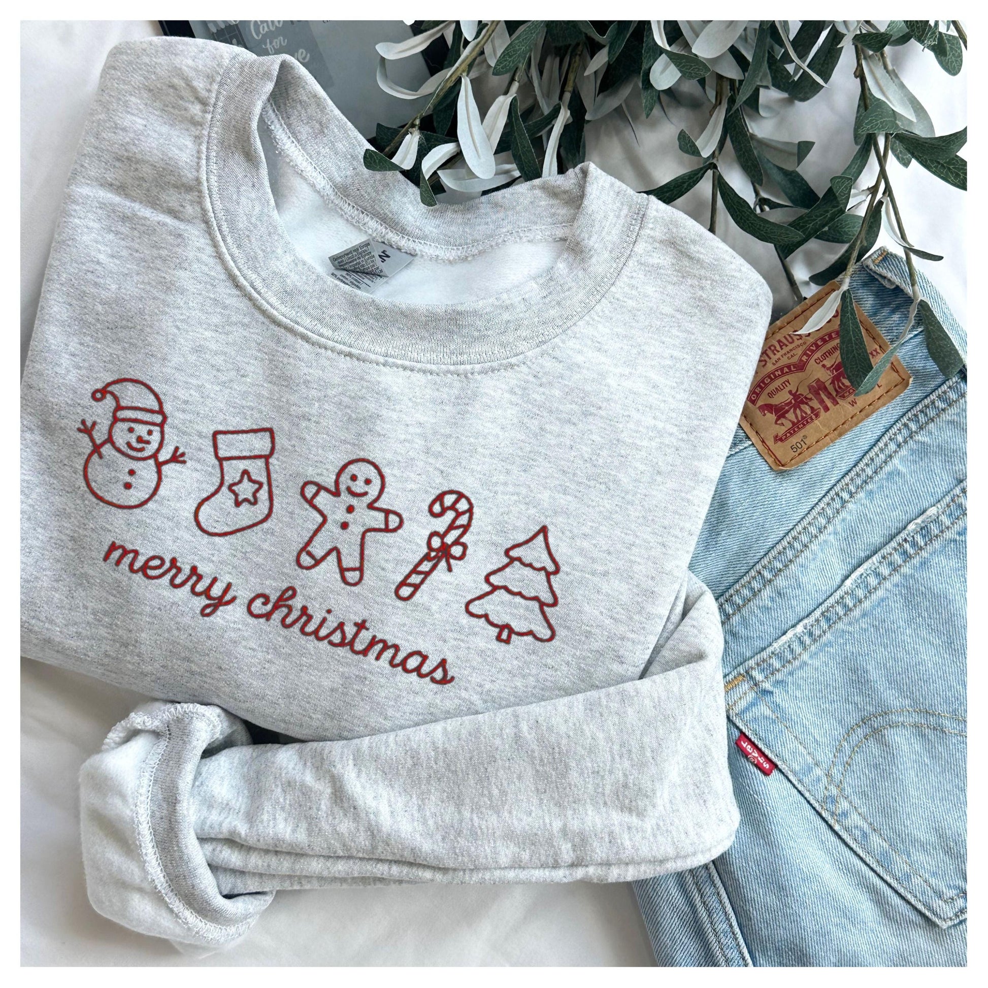 Cozy gray Merry Christmas sweatshirt with red holiday icons including snowman stocking gingerbread man candy cane and tree perfect for holiday outfits and Christmas gifts