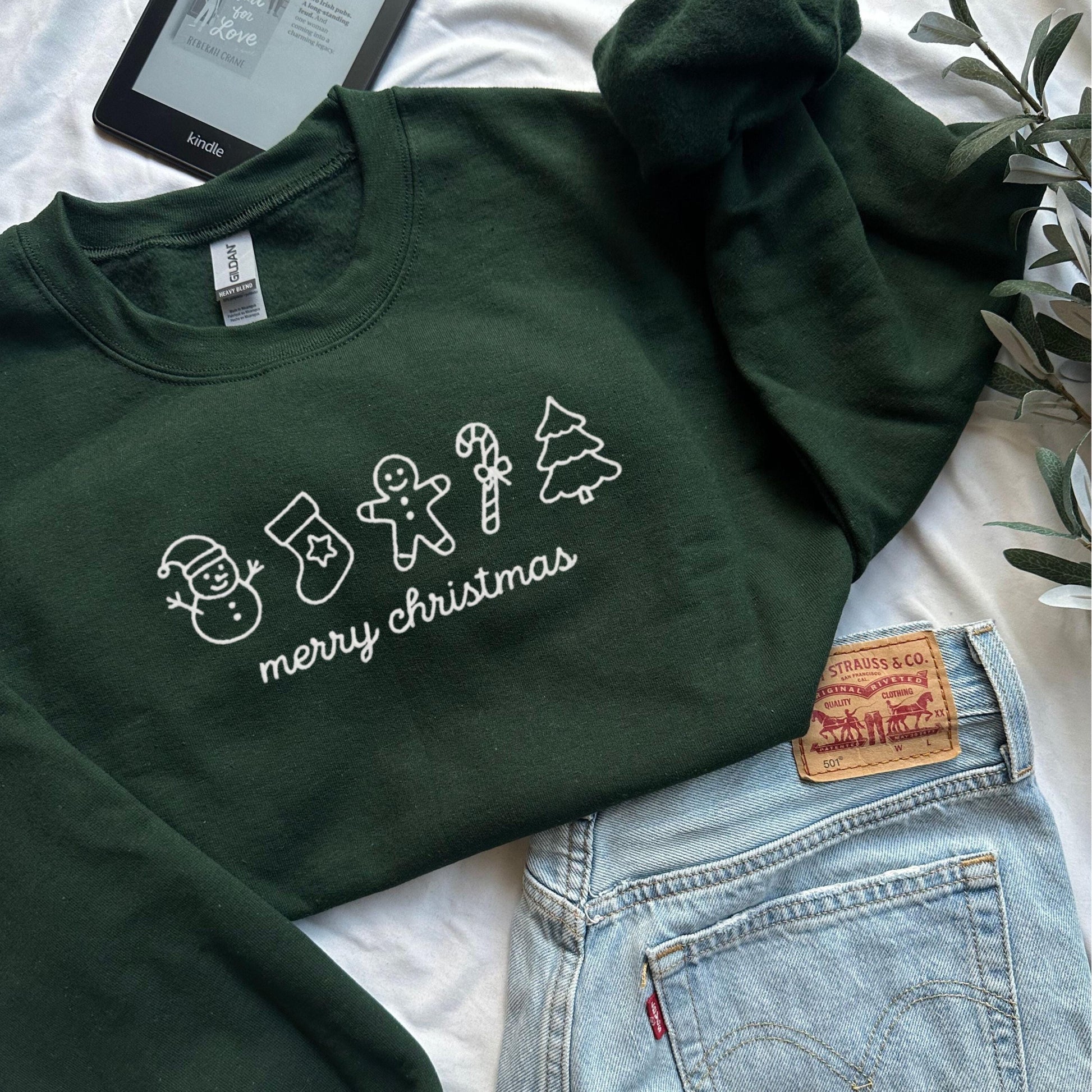 Cozy green Merry Christmas sweatshirt with white holiday icons including snowman stocking gingerbread man candy cane and tree perfect for holiday outfits and Christmas gifts