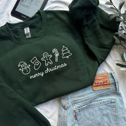 Cozy green Merry Christmas sweatshirt with white holiday icons including snowman stocking gingerbread man candy cane and tree perfect for holiday outfits and Christmas gifts