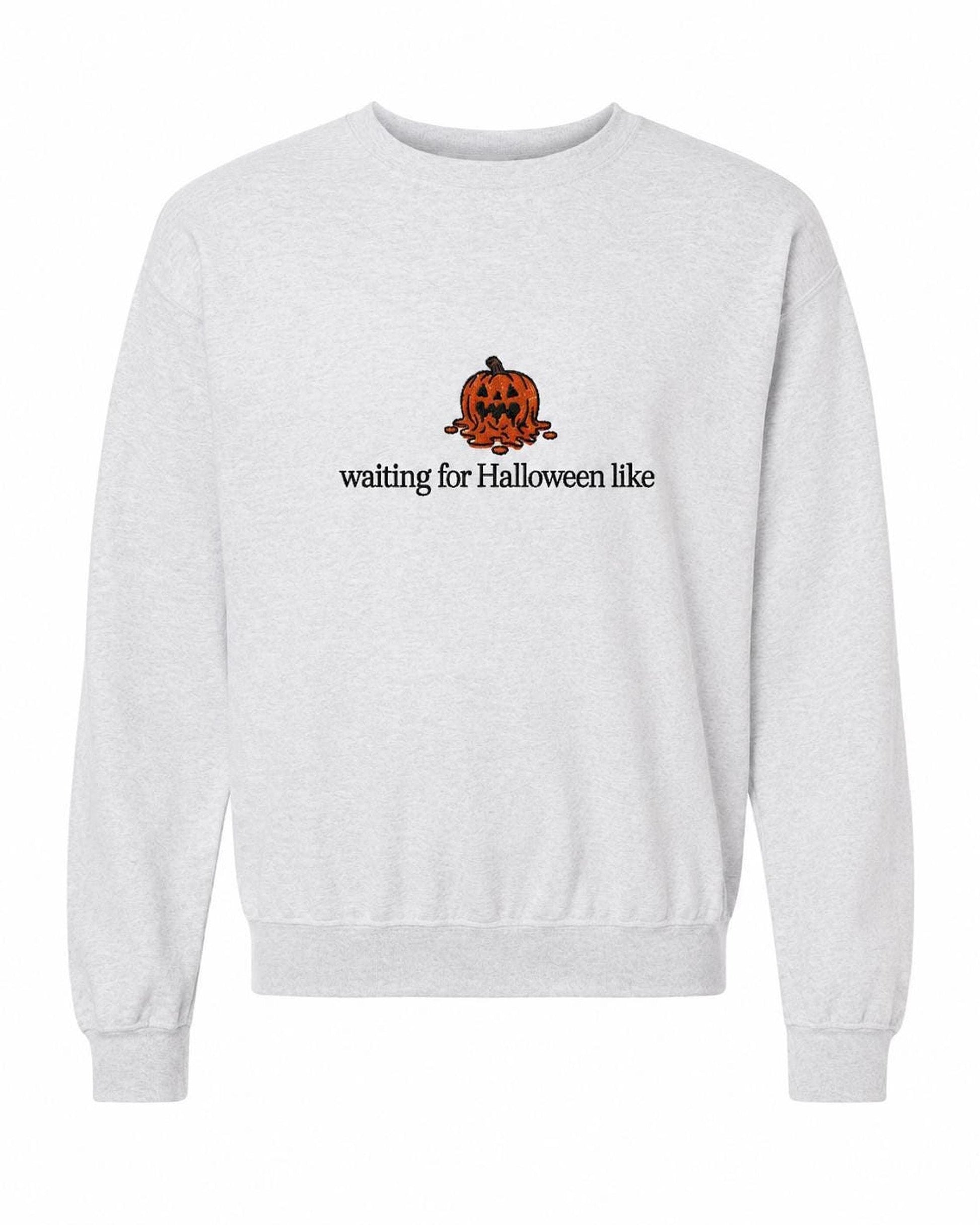 A light gray crewneck sweatshirt with a melted orange jack-o'-lantern and the text "waiting for Halloween like" printed on the front.