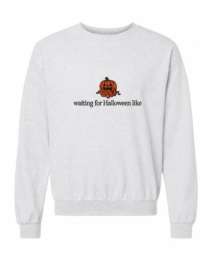 A light gray crewneck sweatshirt with a melted orange jack-o'-lantern and the text "waiting for Halloween like" printed on the front.