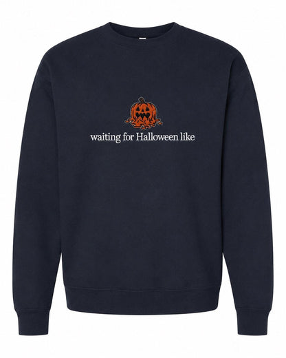 A navy blue crewneck sweatshirt with a melted orange jack-o'-lantern and the text "waiting for Halloween like" printed on the front.