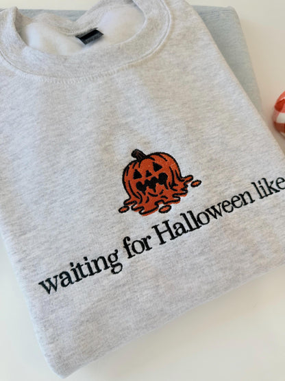 A close-up of a light gray sweatshirt shows an embroidered melting jack-o'-lantern and the text "waiting for Halloween like" with a small red and white plaid pumpkin in the background.